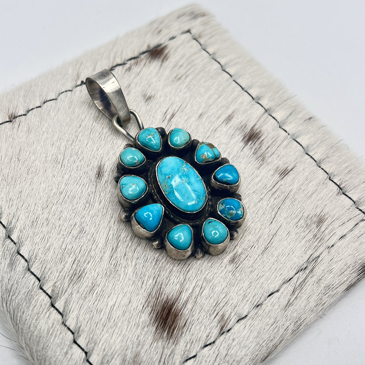 Angled view of the turquoise cluster pendant showing bezels and silver bail