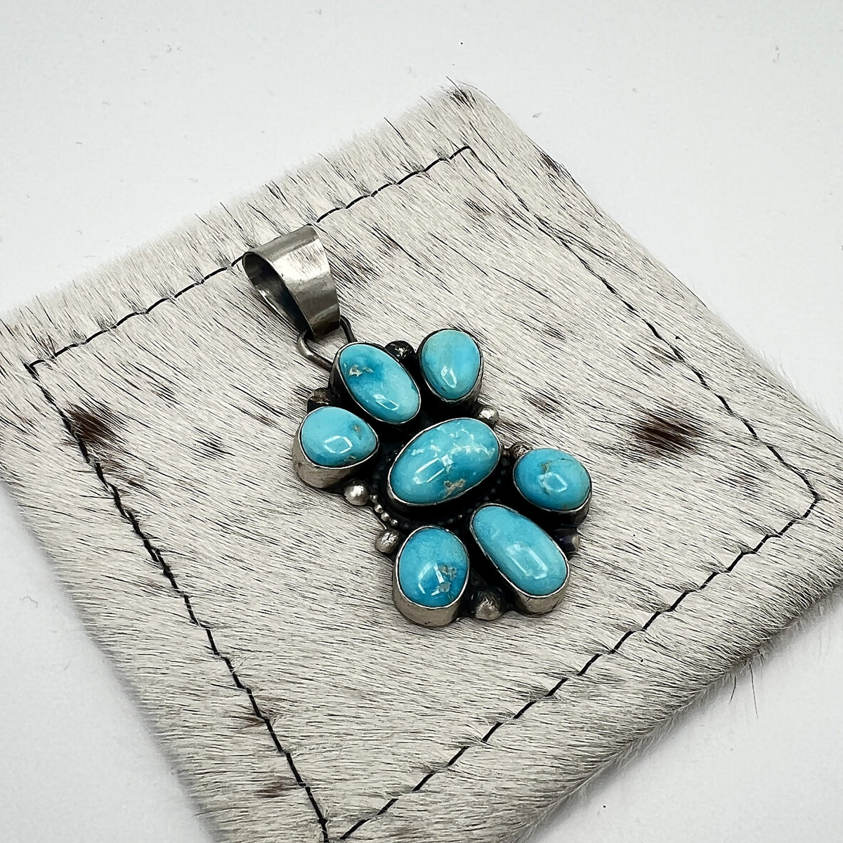 Angled view of the Blue Bird turquoise pendant showing hand-formed bezels and silver dot accents