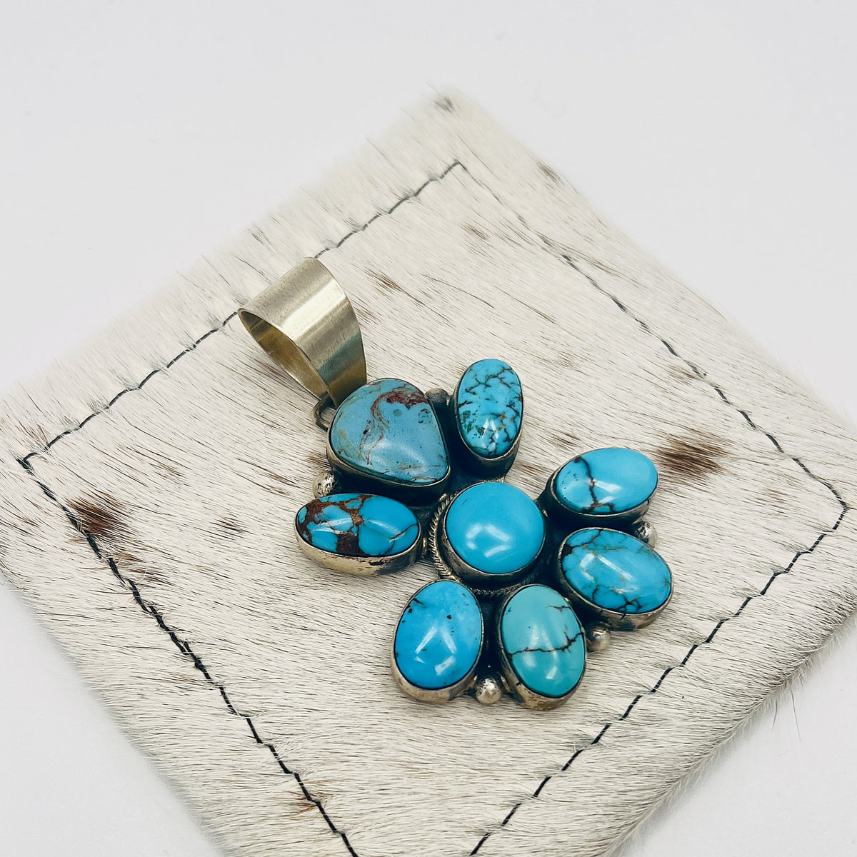 Side view showing the sterling silver bezels and bail of the turquoise cluster pendant